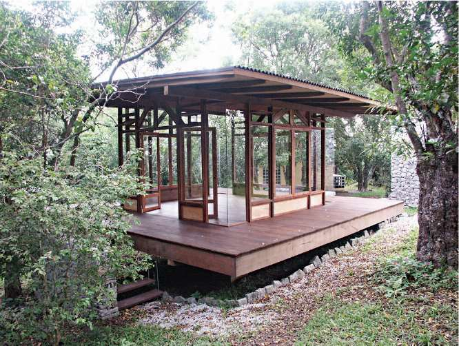 Pavillon de bois et verre au milieu des arbres